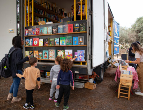 3 ילדים מתעניינים בספרים המוצגים בכניסה למשאית