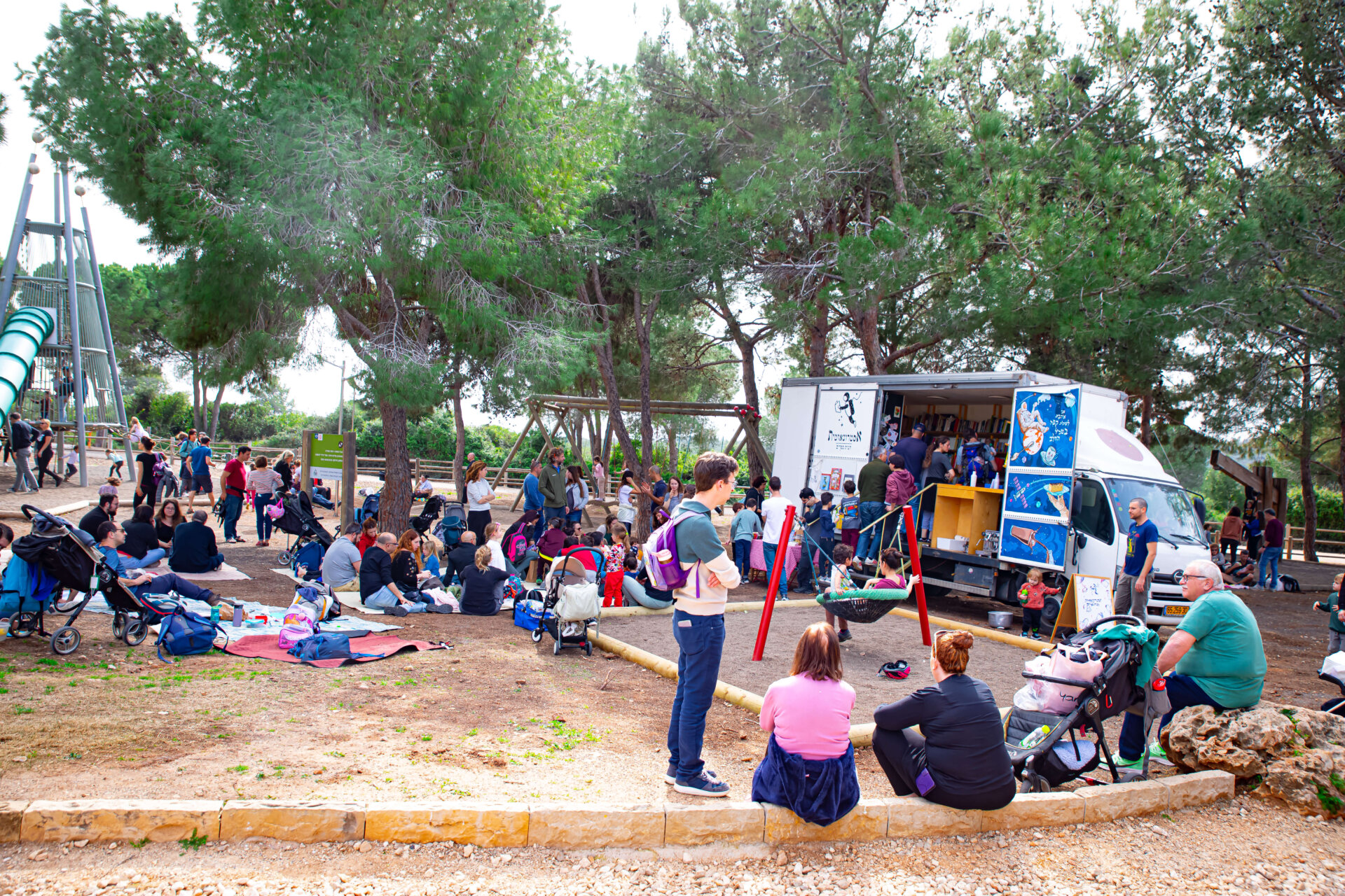 משאית ספרים בגן משחקים עם קהל משפחות מסביב