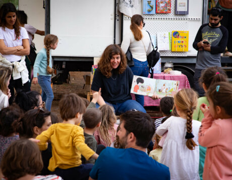 מספרת סיפור מוקפת בילדים ליד משאית הספרים