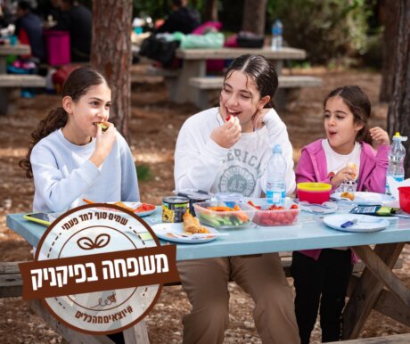 3 בנות יושבות בשולחן ואוכלות במתחם הפיקניק