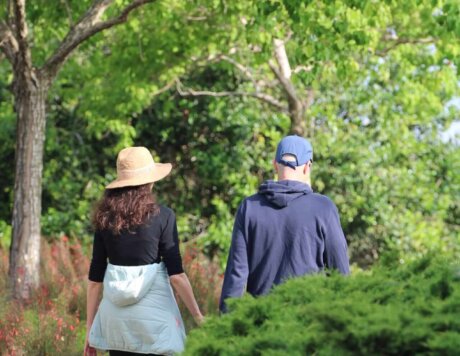 גבר ואישה צועדים בשביל בגן העובר בין עצים וצמחייה