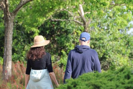 גבר ואישה צועדים בשביל בגן העובר בין עצים וצמחייה